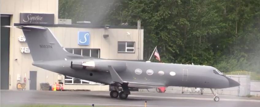 A grey private jet with tail number N163PA parked on a tarmac in front of a Signature Flight Support building.