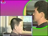 A low-resolution screenshot from a North Korean television broadcast featuring two Asian men in profile against a purple and green graphic background. A smaller inset window shows a profile view of one of the men. A logo is visible in the top left corner.