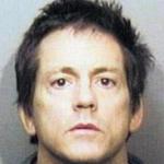 A mugshot of a Caucasian man with dark, messy hair and a neutral expression.