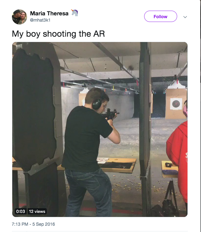A screenshot of a tweet by Maria Theresa showing a young man with brown hair at an indoor shooting range, aiming an AR-style rifle. He is wearing a black t-shirt and jeans.