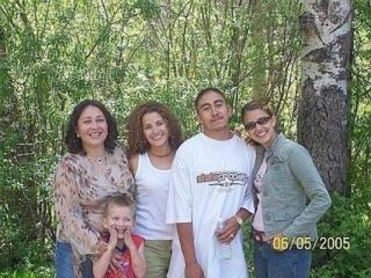 A group photograph of four adults and one child standing outdoors in front of trees, with a date stamp of 06/05/2005.