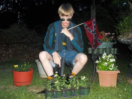 Dylann Roof with Confederate flag and holding the Glock .45 he used to murder 9 God fearing Black people in a South Carolina church June 17