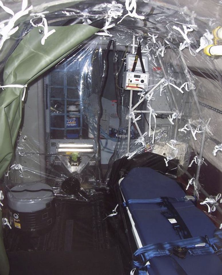 Interior of a specialized medical evacuation aircraft featuring a blue stretcher and clear plastic isolation containment sheeting.