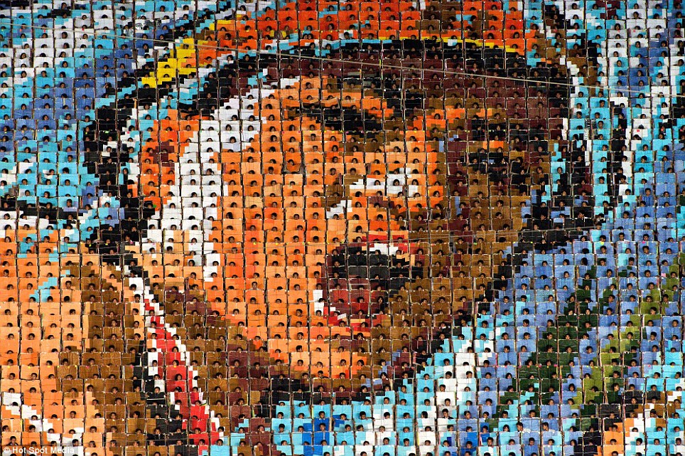 A massive human mosaic in a stadium, likely in North Korea, depicting a portrait of a leader created by thousands of individuals holding up colored cards.