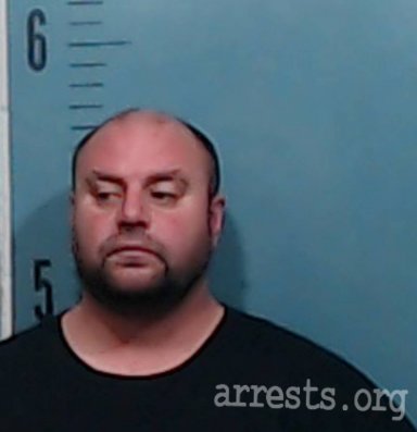 A mugshot of a Caucasian man with a goatee and a balding head, standing against a blue background with a height scale. A watermark for arrests.org is in the bottom right corner.