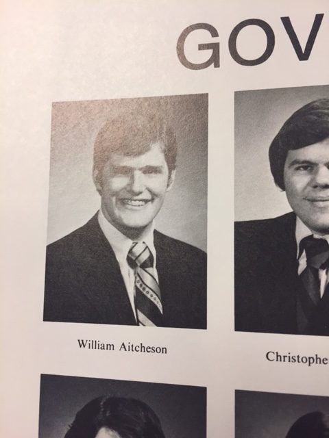 A black and white yearbook-style portrait of a young man identified as William Aitcheson, wearing a suit and striped tie.