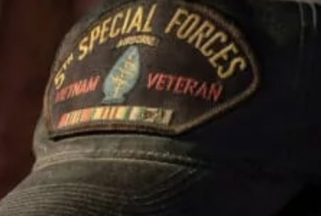 A close-up photograph of a dark baseball cap featuring a patch that reads '5th SPECIAL FORCES AIRBORNE VIETNAM VETERAN' with military service ribbons.
