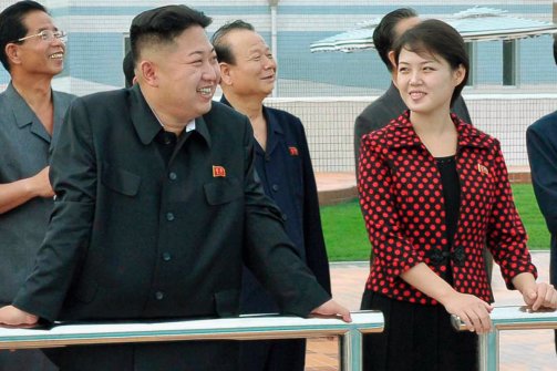 kjuwife97861343292369017.cached Kim Jong-un and his wife Ri Sol-ju standing outdoors with officials in North Korea.