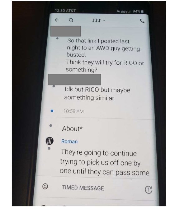 A photograph of a smartphone screen showing a chat log between individuals discussing the arrest of an Atomwaffen Division (AWD) member and potential RICO charges.