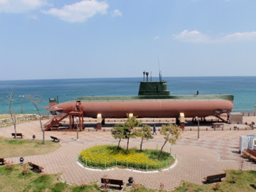 A North Korean Sang-O class midget submarine on display at a coastal park in South Korea, overlooking the sea.